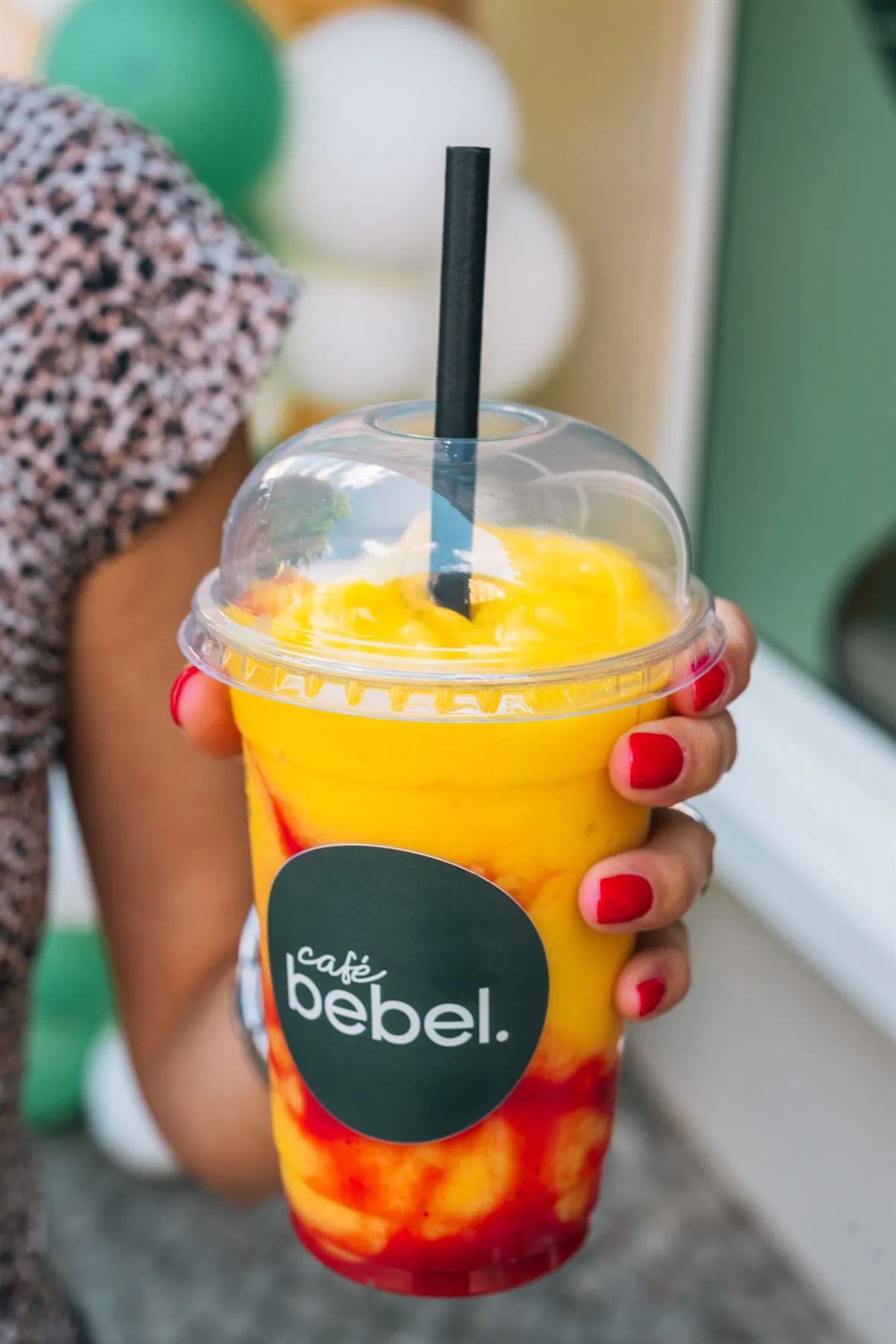 Mango Cloud Drink im Café-Bebel-Becher vor grüner Wand