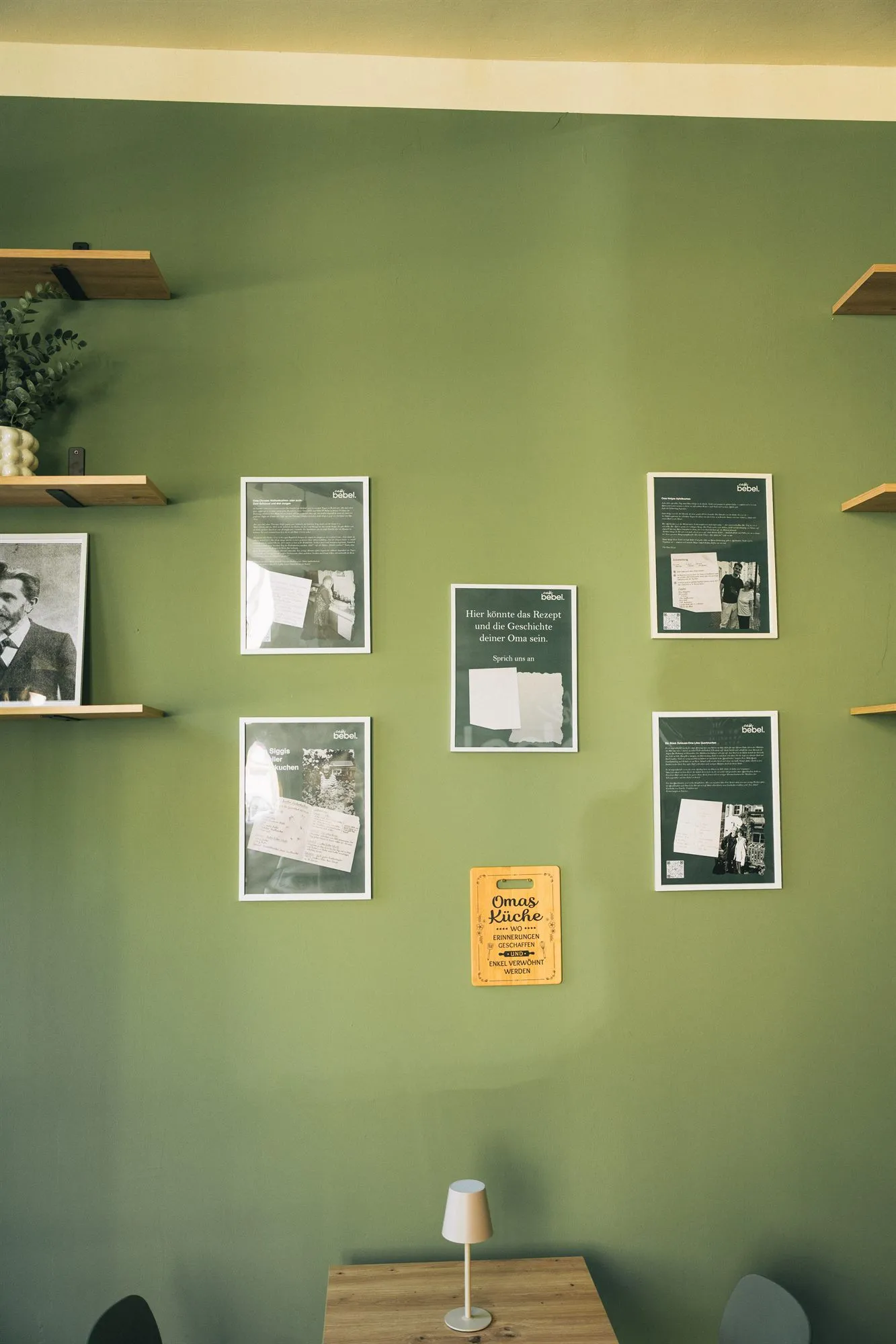 Gemütliche Ecke im Café Bebel mit grüner Wand und gerahmten Fotos