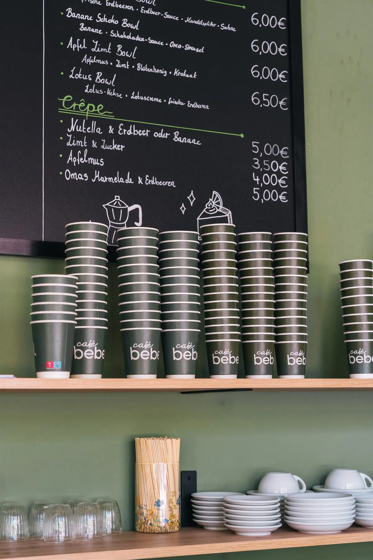 Szene aus dem Café Bebel mit handgeschriebener Tafel und Bechern